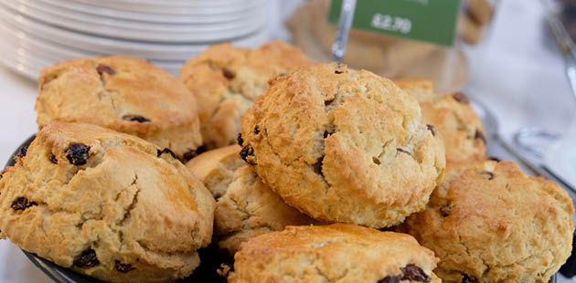 A plate of scones. The scones are crumbling and piled plentiful on the plate.